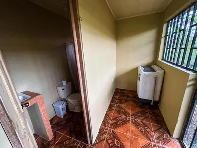 a small bathroom with a toilet and a window at Cabaña La Conquista in Sarapiquí