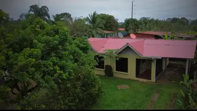 a house with a pink roof and a yard at Cabaña La Conquista in Sarapiquí