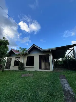 a white house with a grass yard in front of it at Cabaña La Conquista in Sarapiquí