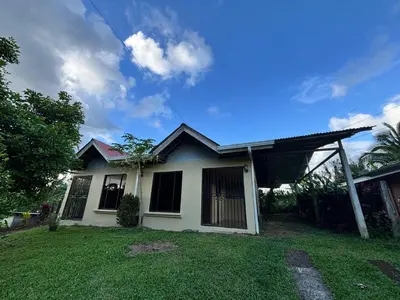 a small white house with a grass yard at Cabaña La Conquista in Sarapiquí