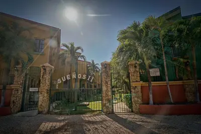 a gate in front of a building with palm trees at 2BR Townhome in Tamarindo• Pool • Walk to Beach in Tamarindo