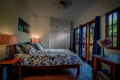 a bedroom with a bed in a room with windows at 2BR Townhome in Tamarindo• Pool • Walk to Beach in Tamarindo