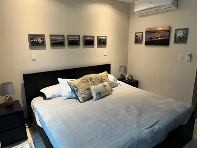 a bedroom with a bed with pillows and pictures on the wall at Beachside 1st Floor Condo Near Flamingo & Conchal in Santa Cruz