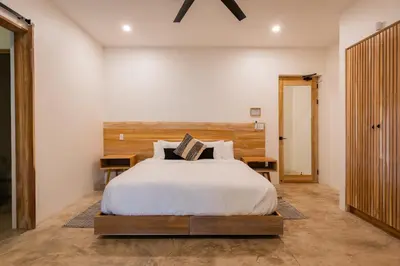 a bedroom with a bed with a wooden headboard at NEW Modern 6BR, Pool, Walk 2 Beach, Sleeps 20 in Playa Guiones