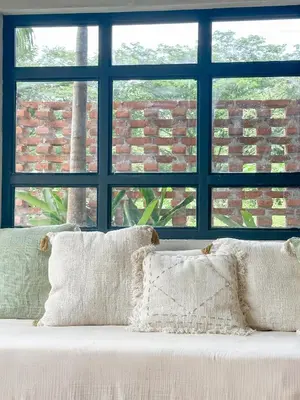 a white couch with pillows in front of a window at Las chozas I in Tamarindo