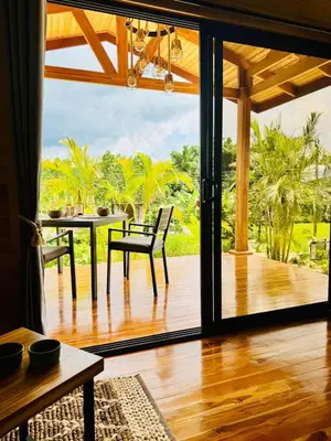 a living room with a large glass door with a table at Refugio del Ocaso - neues Teak-Haus mit Garten in Hojancha