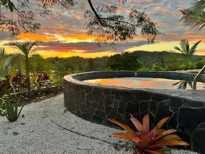 a hot tub with a sunset in the background at Refugio del Ocaso - neues Teak-Haus mit Garten in Hojancha
