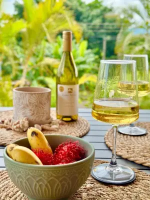 a bowl of fruit and a glass of wine on a table at Refugio del Ocaso - neues Teak-Haus mit Garten in Hojancha