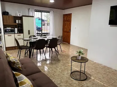 a living room with a couch and a table and chairs at Sonrisas del Arenal, cerca de La Fortuna de SC in Chachagua