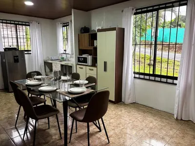 a dining room with a table and chairs and a kitchen at Sonrisas del Arenal, cerca de La Fortuna de SC in Chachagua