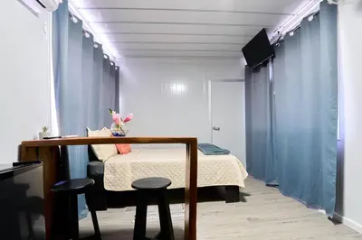 a bedroom with a bed and a table and two stools at Módulos Yunni in Uvita