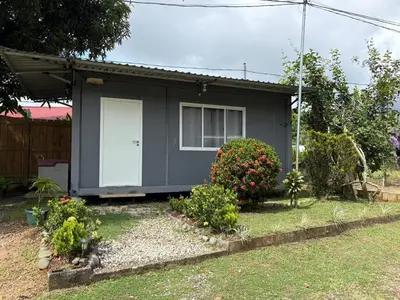 a gray house with a white door and some bushes at Módulos Yunni in Uvita