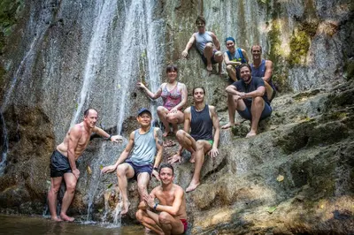 a group of people sitting on rocks in front of a waterfall at Rainforest Glamping, Forest Bathing in the Osa Region in Ciudad Cortés