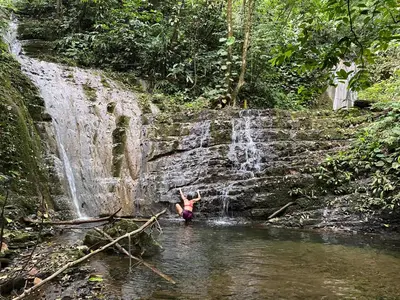 a person swimming in a stream in front of a waterfall at Rainforest Glamping, Forest Bathing in the Osa Region in Ciudad Cortés
