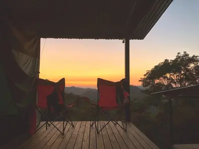 two chairs sitting on a deck watching the sunset at Rainforest Glamping, Forest Bathing in the Osa Region in Ciudad Cortés