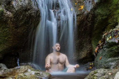 a man sitting in front of a waterfall at Rainforest Glamping, Forest Bathing in the Osa Region in Ciudad Cortés