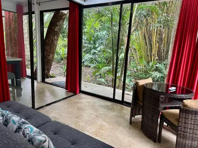 a living room with red curtains and a table and chairs at Villa Lapas and Apartment, Central, Pool and lots of Wildlife in Manuel Antonio