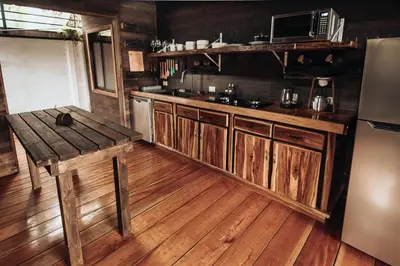 a kitchen with wooden floors and a refrigerator and a table at El Carpintero Guest House in Fortuna