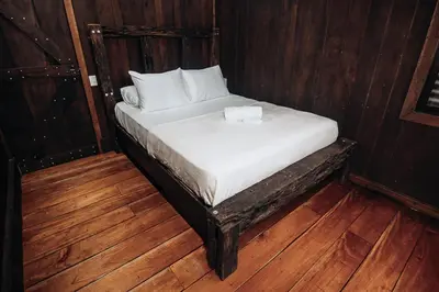 a small bed in a room with wooden floors at El Carpintero Guest House in Fortuna