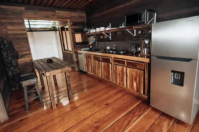 a kitchen with wooden floors and a refrigerator and a table at El Carpintero Guest House in Fortuna