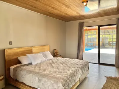 a bedroom with a bed and a sliding glass door at NulaKai Boutique Apartments in Santa Teresa Beach