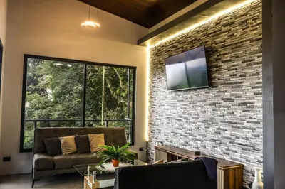 a living room with a brick wall and a tv at Villa Centinela in Monteverde Costa Rica