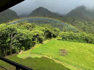 a rainbow over a field with trees and a hill at Villa Centinela in Monteverde Costa Rica