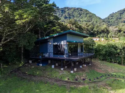 a blue house with mountains in the background at Villa Centinela in Monteverde Costa Rica