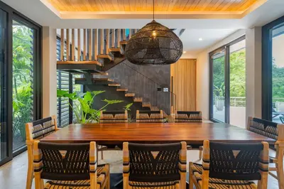 a dining room with a table and chairs and a staircase at Modern 4BR with Pool, Walk2Beach, Yoga Deck, Sleeps 14 in Nosara