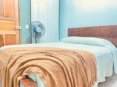 a bedroom with a bed with an orange blanket and a fan at Rous place# 2 in Fortuna