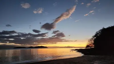 a sunset over a body of water at Teak house in a forest above the beach