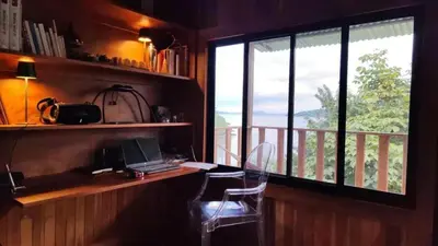 a room with a desk with a laptop and a window at Teak house in a forest above the beach