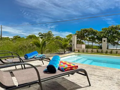 a pool with two lounge chairs next to a swimming pool at Playa Hermosa 44 - Beach House Getaway in Playa Hermosa