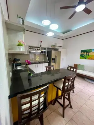 a kitchen with a black counter top and chairs at Beachfront apartment in Jacó in Tapantí