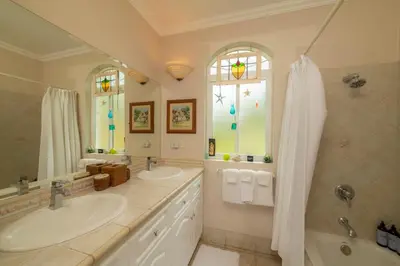 a bathroom with two sinks and a shower at Colina 8E 2 bdr Garden View in Los Suenos in Herradura