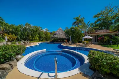 a swimming pool at a resort with chairs and trees at Colina 8E 2 bdr Garden View in Los Suenos in Herradura