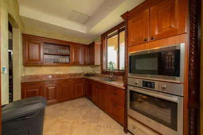 a kitchen with wooden cabinets and stainless steel appliances at Casa Garmus 10 bdrs ocean views in Los Suenos in Herradura