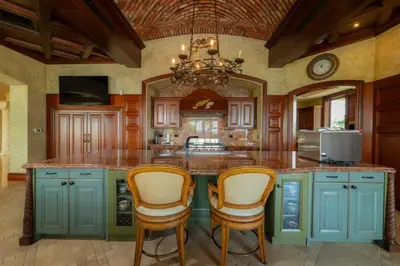 a kitchen with blue cabinets and a large island with chairs at Casa Garmus 10 bdrs ocean views in Los Suenos in Herradura