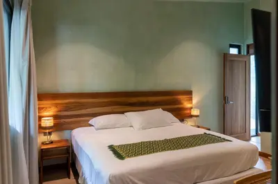 a bedroom with a large white bed with a wooden headboard at Nakama Nosara in Nicoya