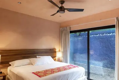 a bedroom with a bed with a ceiling fan and a window at Nakama Nosara in Nicoya