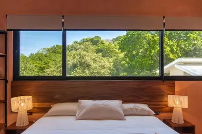 a bedroom with a large window above a bed at Nakama Nosara in Nicoya