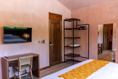 a bedroom with a bed and a tv on the wall at Nakama Nosara in Nicoya