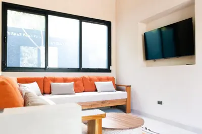 an orange couch in a living room with windows at Nakama Nosara in Nicoya