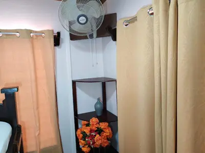a room with a fan and a shelf with flowers at Charming Small House, Near the beach & Waterfalls in Platanillo