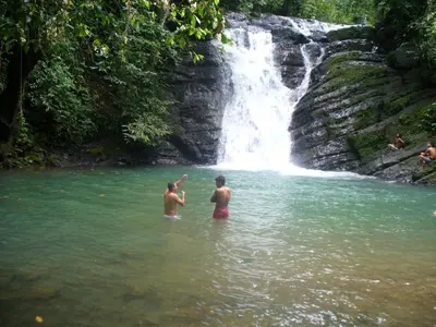 two men standing in the water in front of a waterfall at Charming Small House, Near the beach & Waterfalls in Platanillo