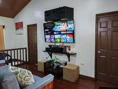 a living room with a couch and a tv on the wall at Charming Small House, Near the beach & Waterfalls in Platanillo