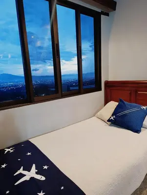 a bedroom with a bed with a view of the city at Hotel Mirador Mayday Mountain View in Alajuela City