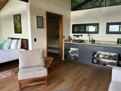 a bedroom with a bed and a sink and a chair at BiBO Casa Savia in Monteverde Costa Rica