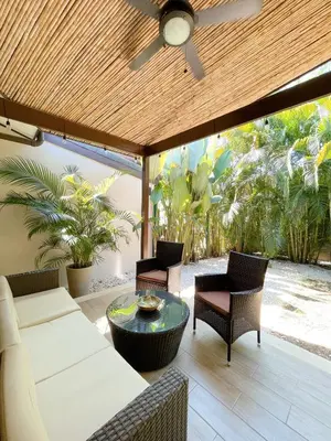 a patio with a ceiling fan and chairs and a table at Beach House & Resort Amenities at Ciudad del Mar Jaco in Jacó