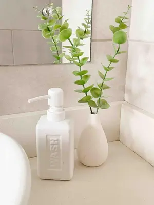 a white bottle of soap and a vase with a plant at Beach House & Resort Amenities at Ciudad del Mar Jaco in Jacó